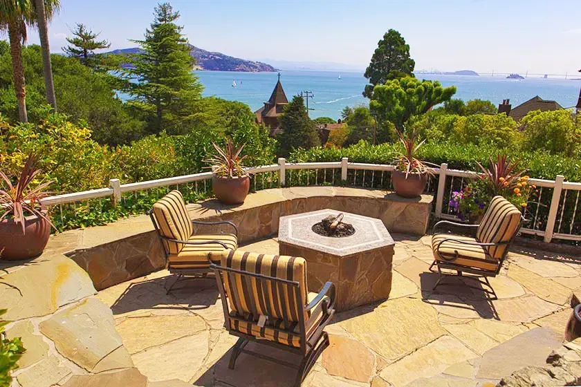 Stone patio with a fire pit and a view over the bay